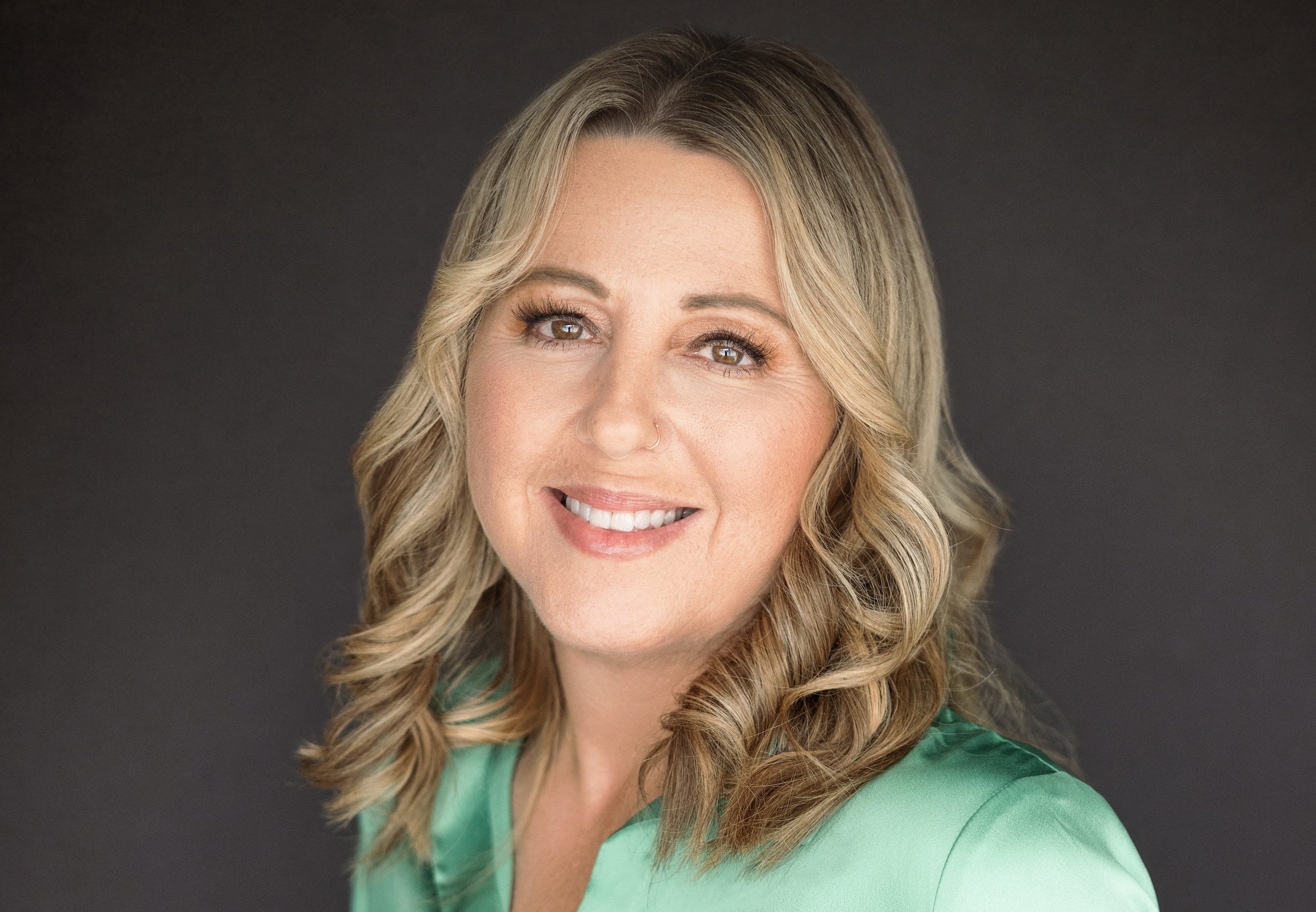 CEO wearing a light green blouse against a dark background